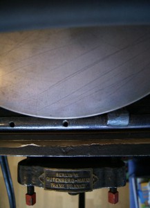 Rollers apply printing ink on a bed of type, then a sheet of paper is pressed on the type in order to transfer the ink.